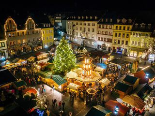 Weimarer Weihnacht am Abend Ein festlich beleuchteter Weihnachtsmarkt mit einem großen, geschmückten Baum und zahlreichen Ständen, die Menschen anziehen.