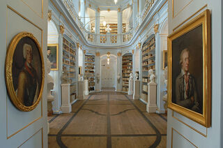 Anna Amalia Bibliothek Zwei Porträts in goldenen Rahmen hängen an den Wänden, während das Licht sanft durch den Raum strömt.