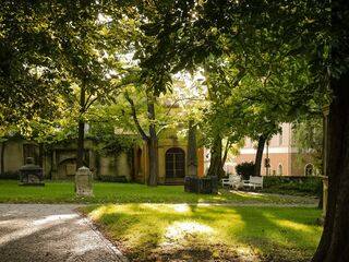 Jakobskirchhof mit Kassengewölbe Eine malerische Szene mit schattenspendenden Bäumen, einem gepflasterten Weg und einem charmanten, historischen Gebäude im Hintergrund.