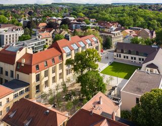 Hauptgebäude der Bauhaus-Universität Weimar Die Szene zeigt eine Mischung aus historischen und modernen Gebäuden, umgeben von üppigem Grün und einem einladenden Platz.
