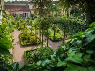Kirms-Krackow-Haus Ein ruhiger Garten mit gepflegten Beeten und einem geschwungenen Pfad, auf dem zwei Menschen entspannt spazieren.