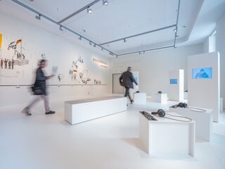 In der Ausstellung im neuen Museum Zwangsarbeit, Foto: Thomas Müller, Museum Zwangsarbeit im Nationalsozialismus Der Raum ist minimalistisch gestaltet, mit weißen Wänden und Podesten, die audiovisuelle Inhalte und historische Informationen bieten.