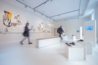 In der Ausstellung, Foto: Thomas Müller, Museum Zwangsarbeit im Nationalsozialismus Der Raum ist minimalistisch gestaltet, mit weißen Wänden und Podesten, die audiovisuelle Inhalte und historische Informationen bieten.