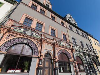 Cranach-Haus am Markt, Foto: Ralph Kallenbach Die Fassade eines alten Hauses zeigt aufwendige Schnitzereien und Fenster mit bunten Rahmen, die die Architektur betonen.