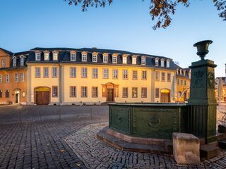 Goethe Nationalmuseum Ein historisches Gebäude mit gelber Fassade und vielen Fenstern, beleuchtet von warmem Licht in der Dämmerung.