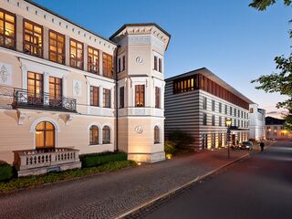 Dorint Am Goethepark Weimar, Foto: Dorint Hotel Weimar Eine ruhige Straße, gesäumt von Bäumen, führt zu einem beeindruckenden Gebäude mit einer Mischung aus traditionellem und modernem Design.