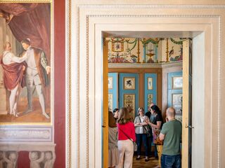 Besucher erkunden das Dichterzimmer im Stadtschloss Weimar Eine Gruppe von Besuchern betrachtet die prächtigen Wandmalereien und die detailreiche Innenarchitektur eines historischen Raumes.